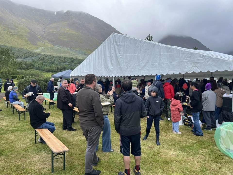 Á markaði á götuveislunni á Flateyri. Tjald í minningarlundinum neðan við varnargarðinn.
